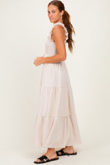 woman wearing a blush pink tiered maxi dress with ruffle details and smocked bodice, styled with black sandals