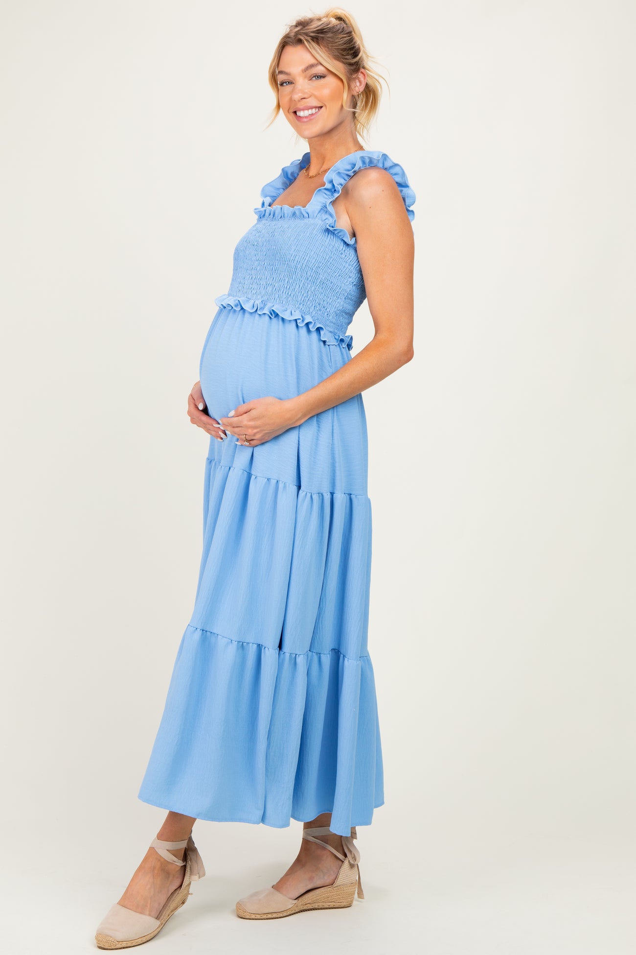 woman wearing a light blue maternity maxi dress with ruffled straps and a smocked bodice, showing her baby bump