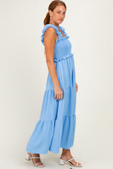 woman wearing a light blue maxi dress with smocked bodice and ruffled straps, standing in profile