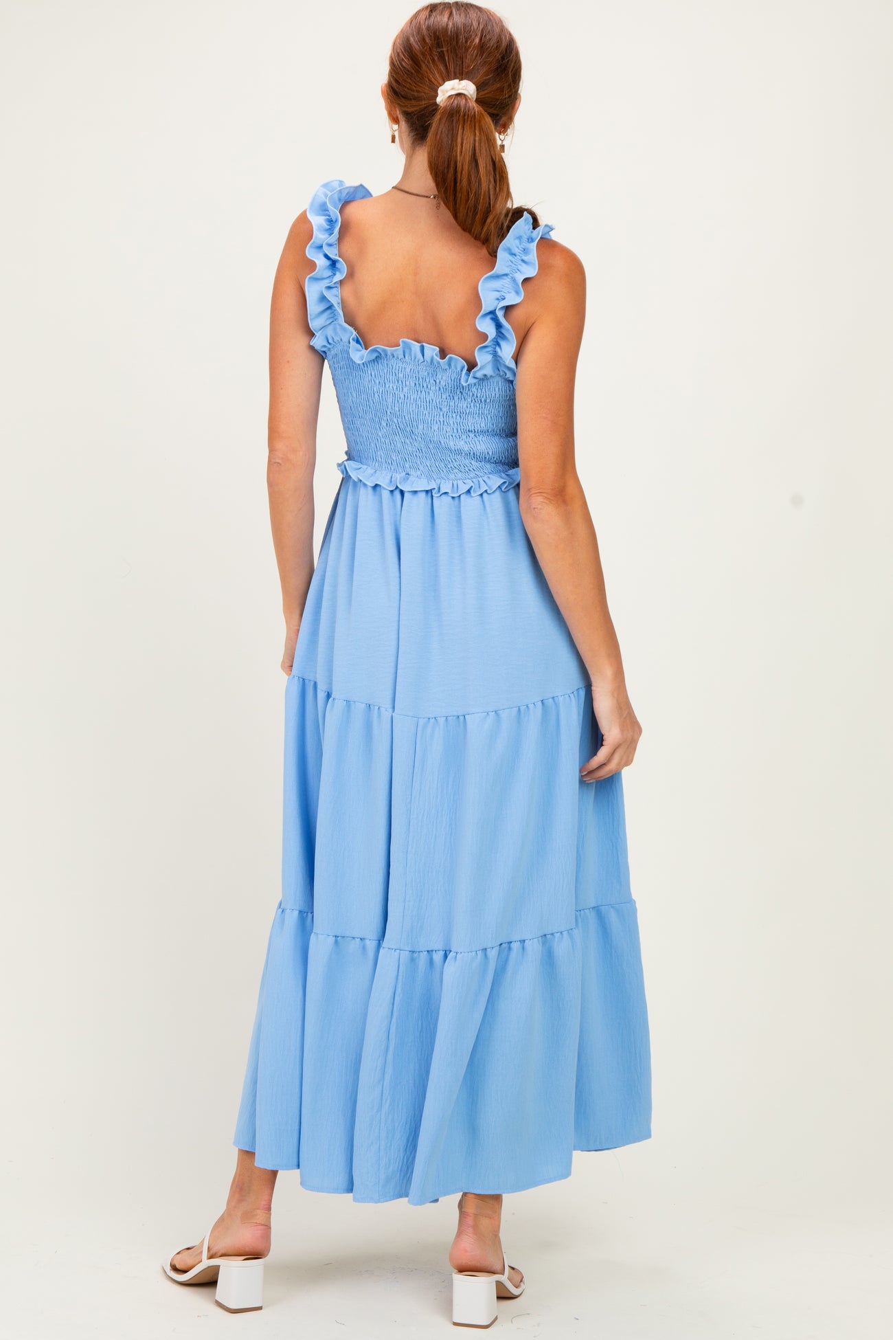 woman wearing a light blue smocked maxi dress with ruffled straps and tiered hem, viewed from the back