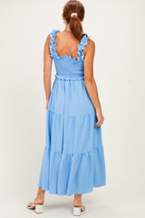 woman wearing a light blue smocked maxi dress with ruffled straps and tiered hem, viewed from the back