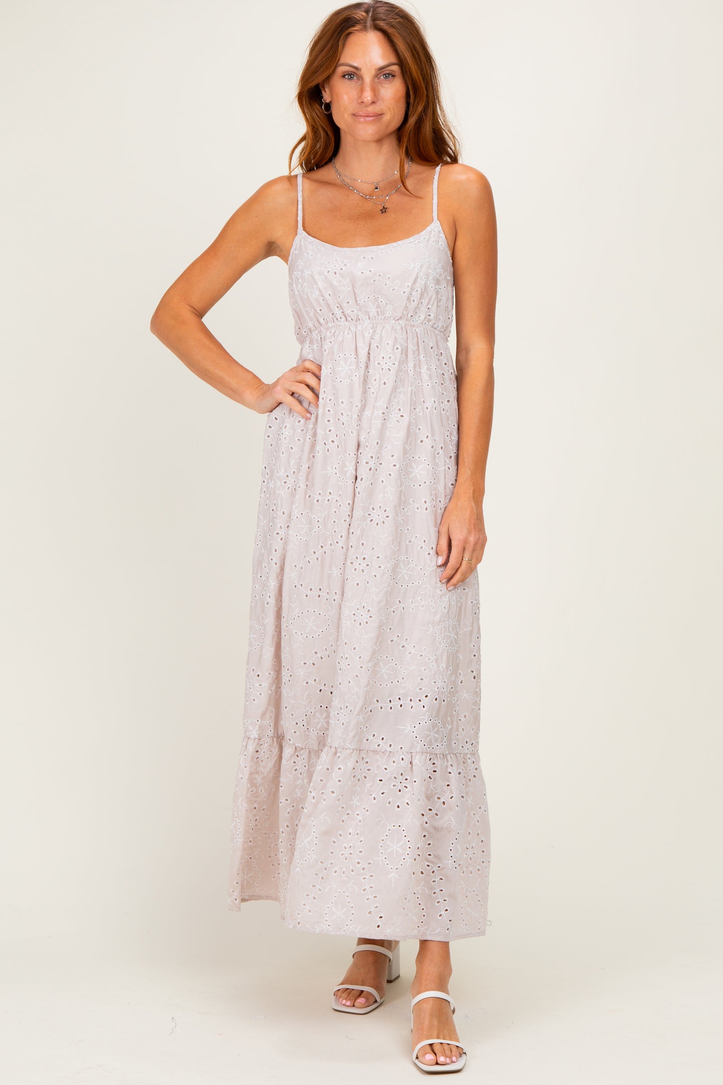 woman wearing a light pink maxi dress with lace detailing and spaghetti straps