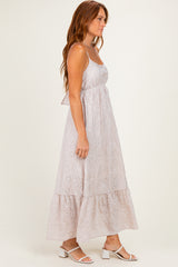 woman wearing a light pink sleeveless maxi dress with eyelet detailing and a tiered skirt