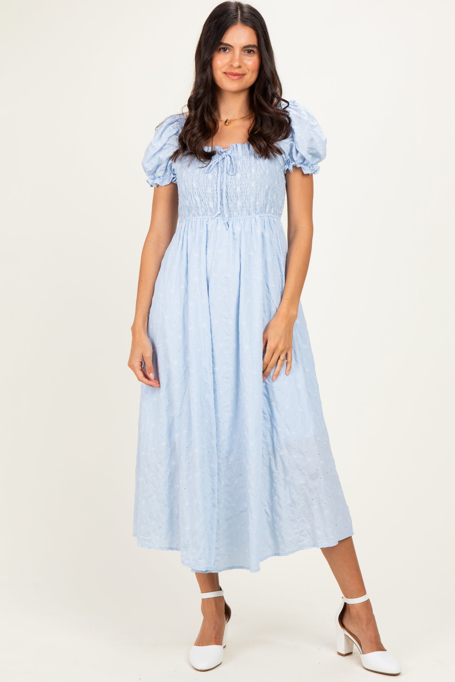 woman wearing a light blue puff sleeve midi dress with a smocked bodice and a flowing skirt