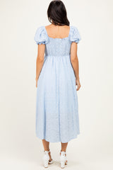 woman wearing a light blue puff sleeve midi dress with a smocked bodice and a flowy skirt, seen from the back