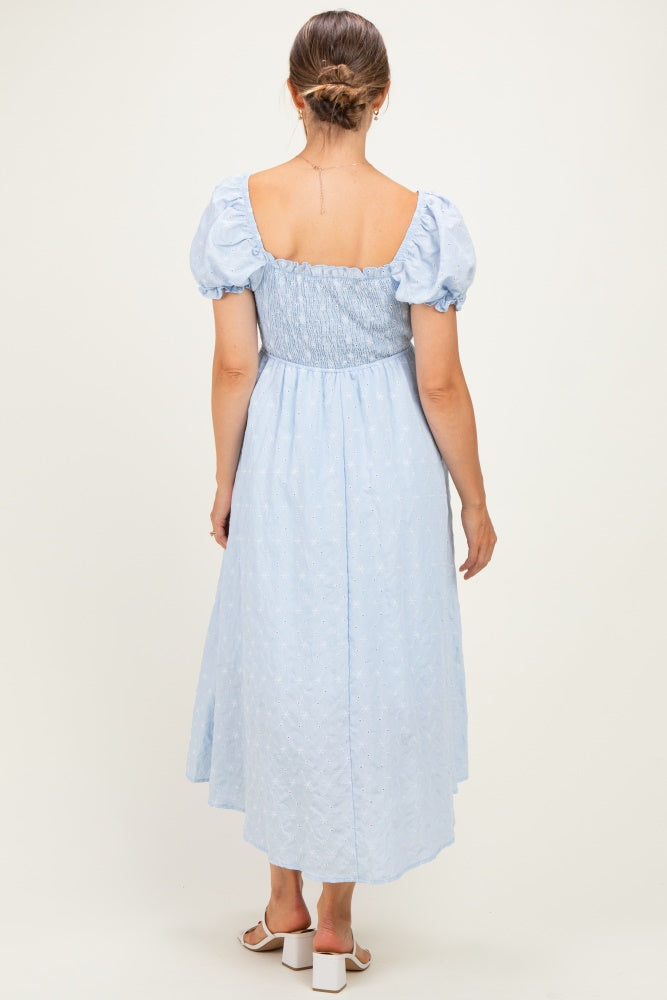 woman wearing a light blue maternity dress with puff sleeves and smocked bodice, showing a flowy skirt from the back