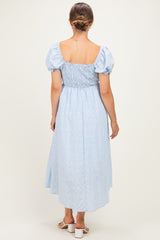 woman wearing a light blue maternity dress with puff sleeves and smocked bodice, showing a flowy skirt from the back