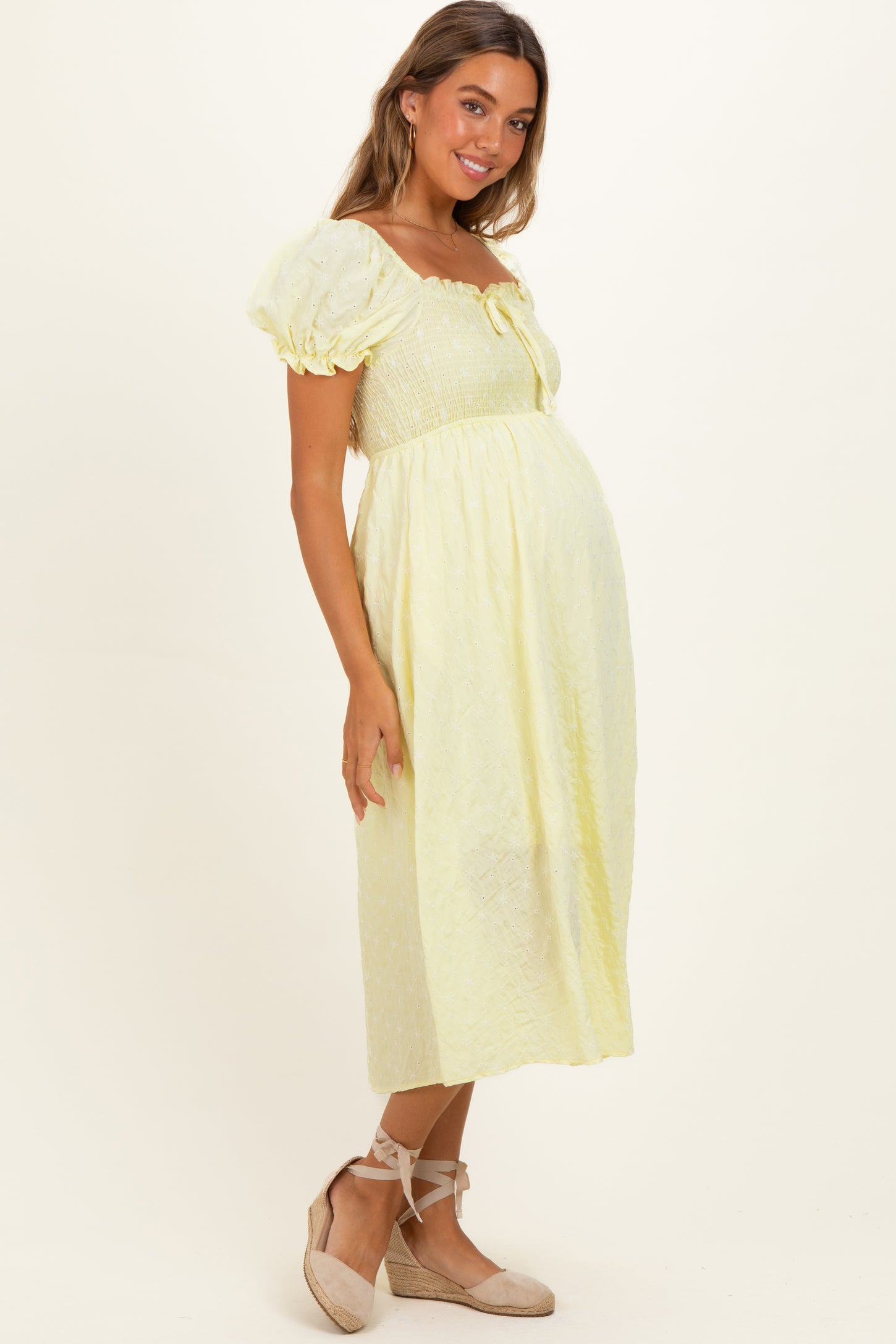 woman wearing a yellow puff sleeve maternity dress with a cinched bodice and a visible baby bump