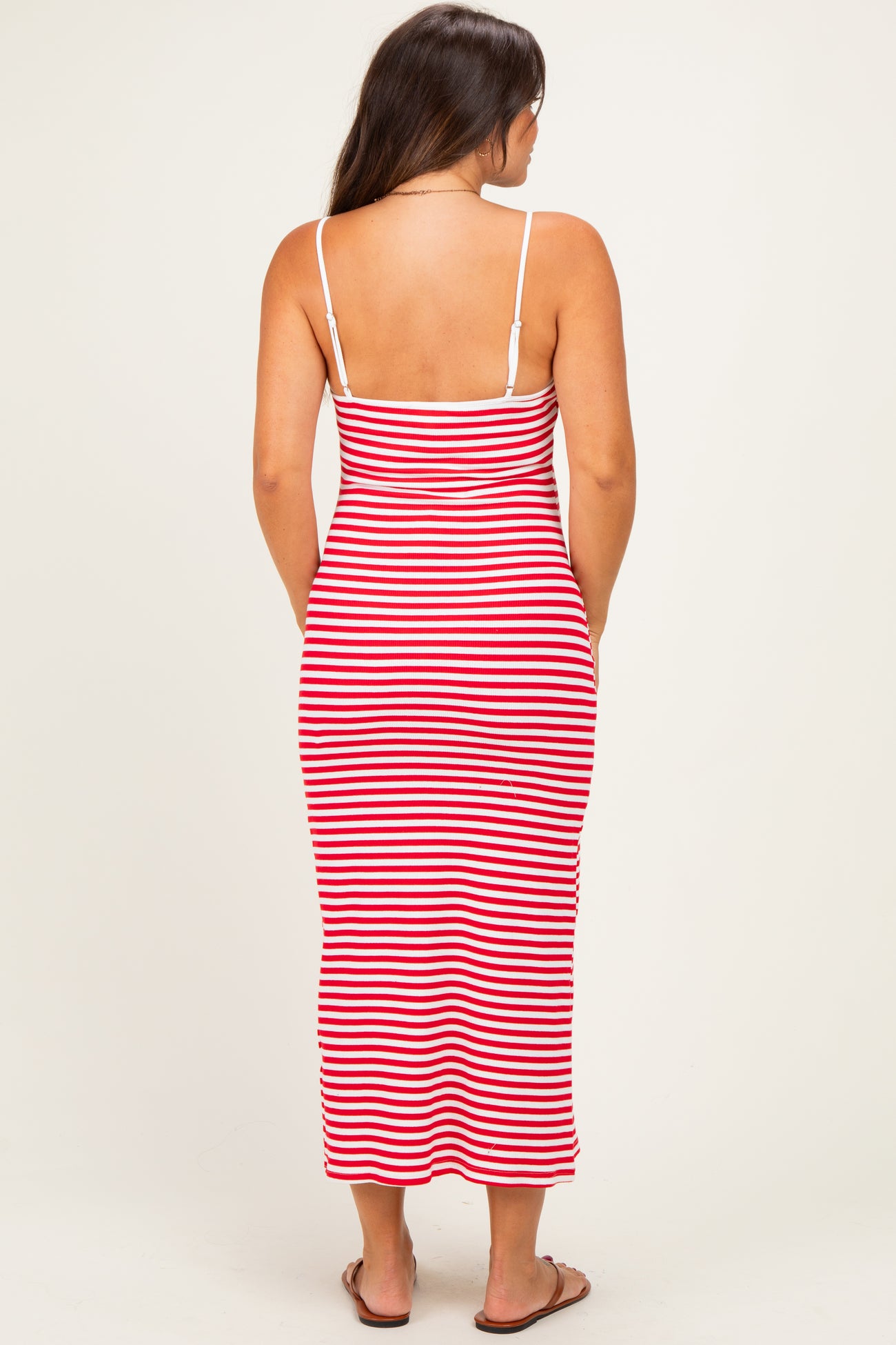 woman wearing a red and white striped maternity maxi dress with thin straps, showing off her baby bump from the back