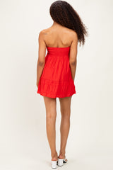 woman wearing a red strapless mini dress with a smocked bodice and tiered ruffle hem