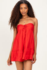 woman wearing a red strapless sundress with a tie front and ruffled hem