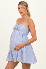 woman wearing a light lavender strapless maternity dress with a ruffled hem and holding her baby bump