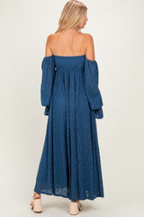 woman wearing a blue off-the-shoulder lace maxi dress with long bell sleeves and a flowy silhouette