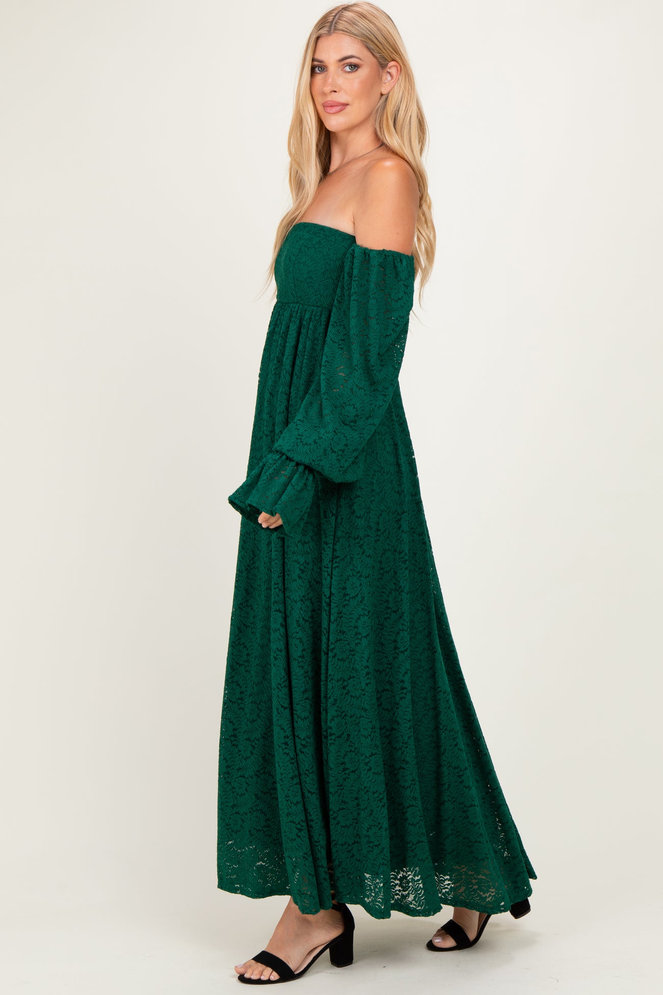 woman wearing a green off-the-shoulder lace maxi dress with long sleeves and a flowy skirt