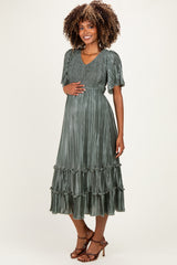 woman wearing a green pleated short sleeve maternity dress with tiered ruffles and a baby bump visible
