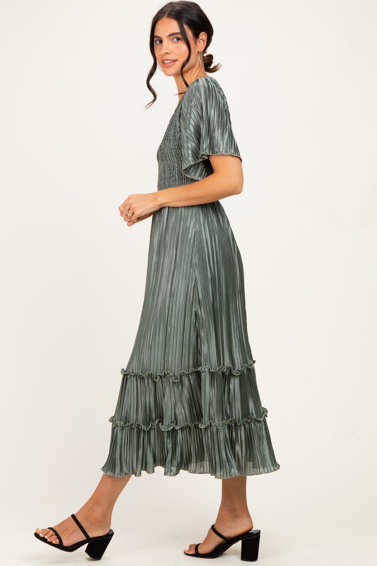woman wearing a sage green pleated midi dress with short sleeves and ruffle details
