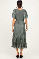 woman wearing a green pleated midi dress with short sleeves and ruffle details, seen from the back