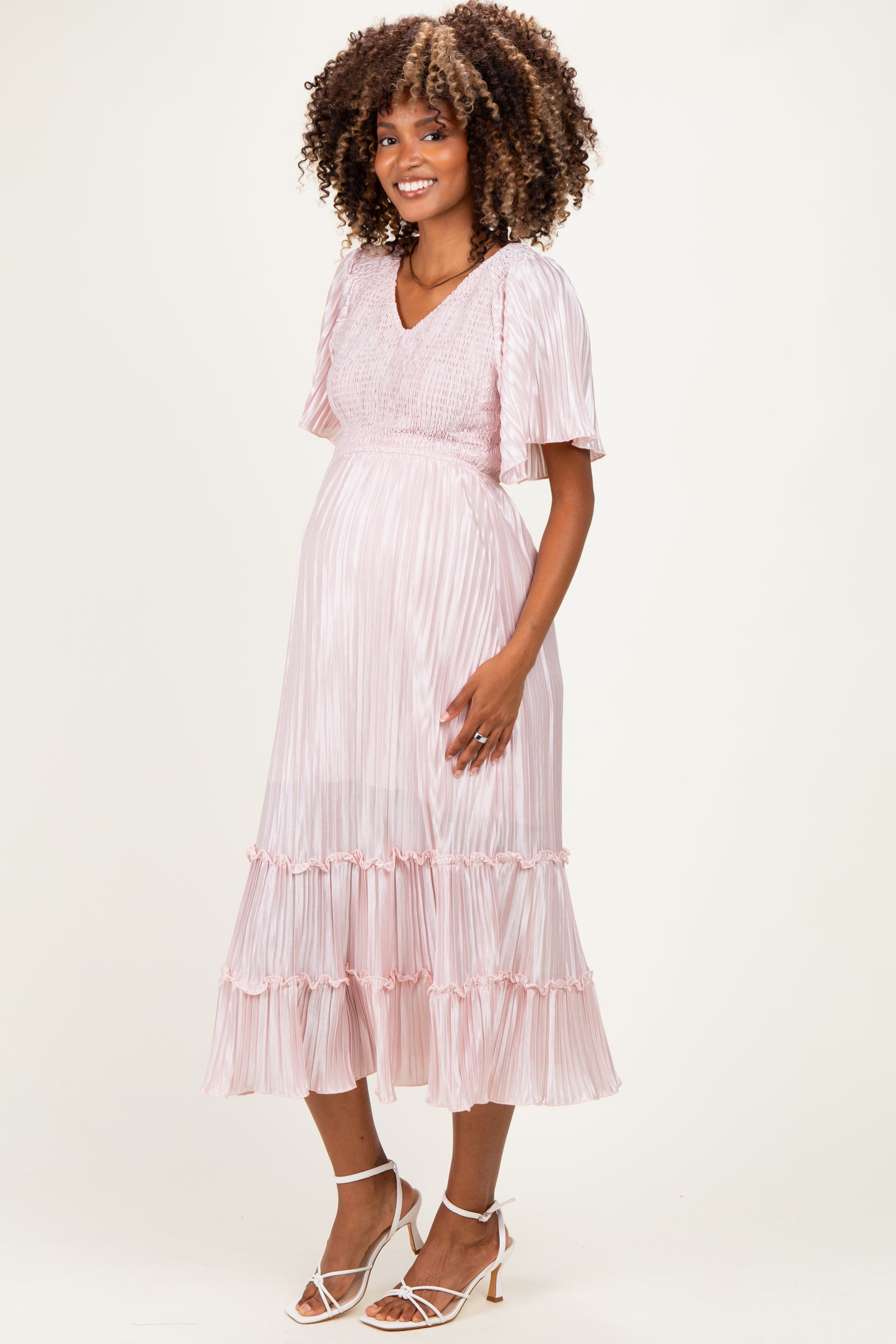 woman wearing a pink striped maternity dress with short sleeves and ruffle hem, highlighting her baby bump