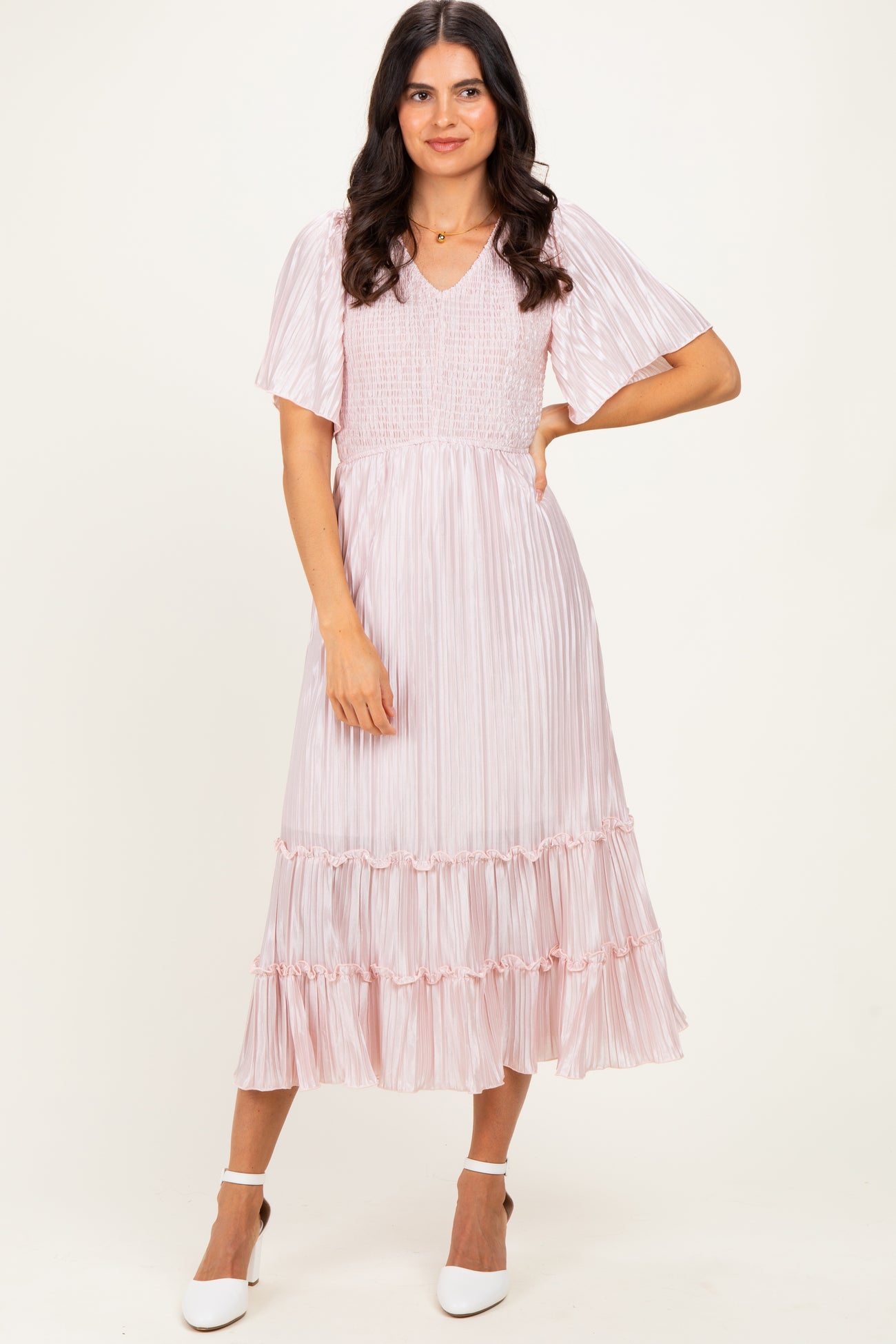 woman wearing a light pink midi dress with a smocked bodice and tiered ruffles, posing against a neutral background
