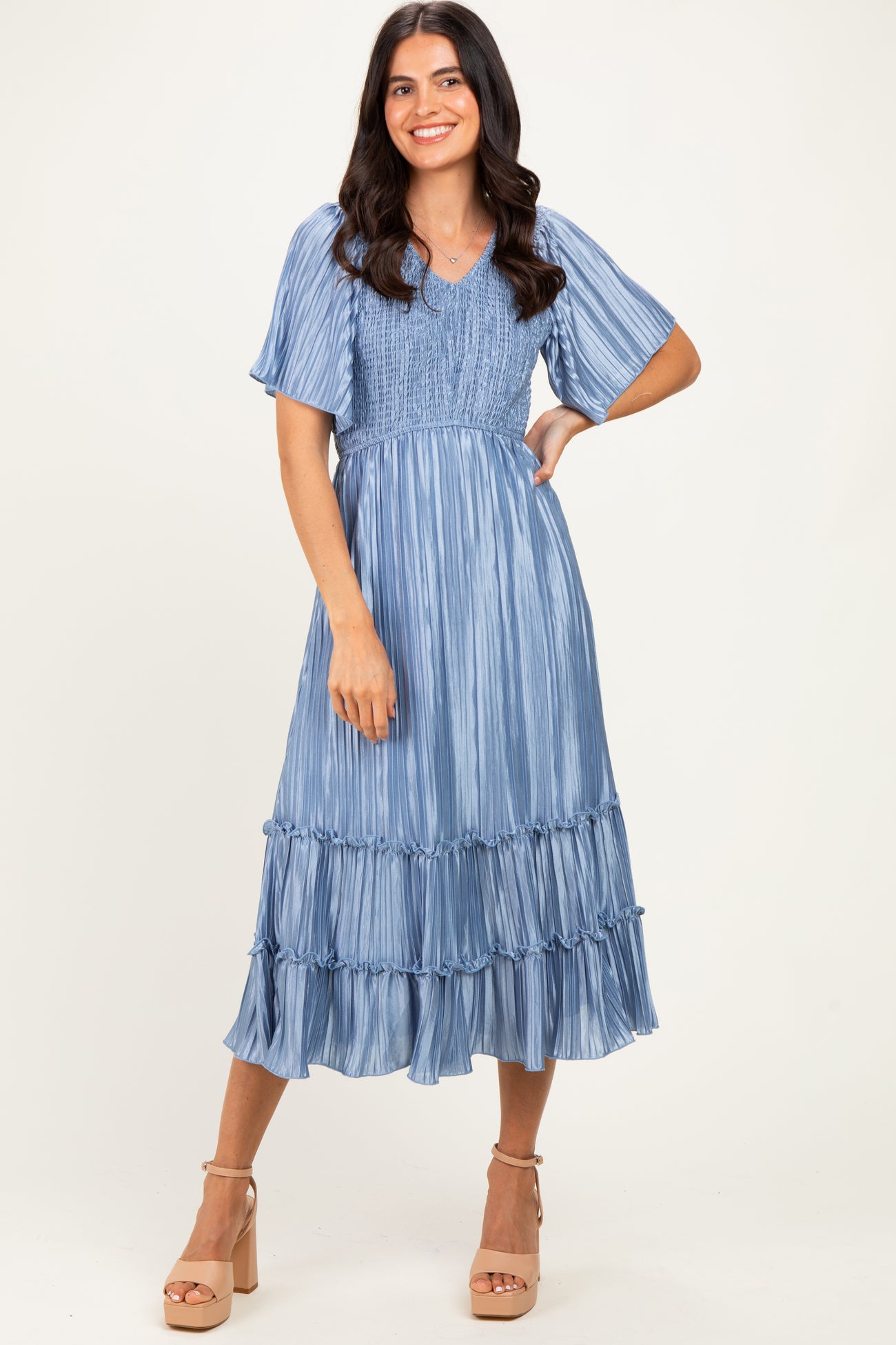woman wearing a blue striped tiered midi dress with short sleeves and a smocked bodice, posing with one hand on her hip