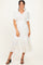 woman wearing a white pleated midi dress with short puff sleeves and a tiered hem, styled with black heeled sandals