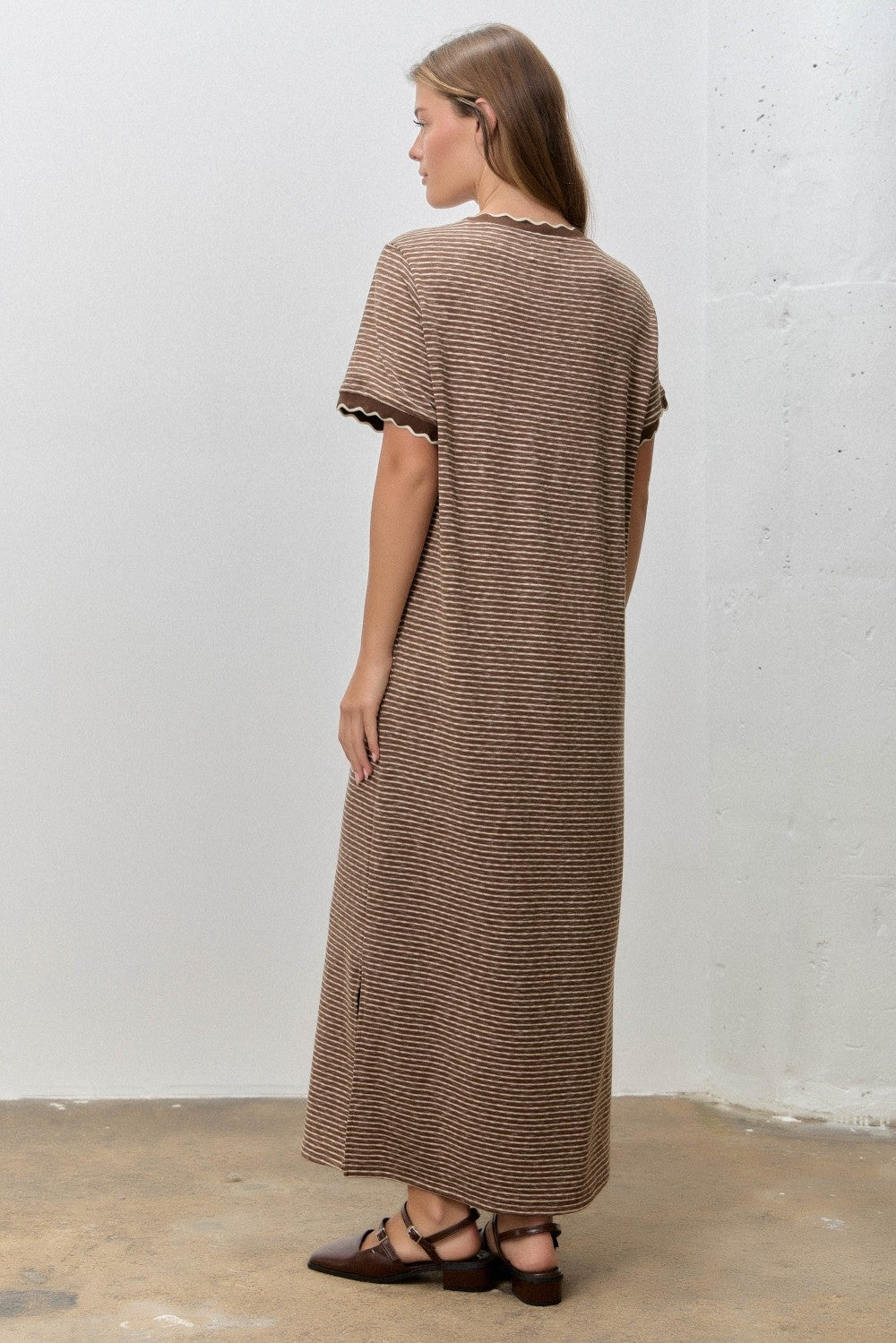 woman wearing a brown striped maxi dress with short sleeves and scalloped edges, viewed from the back