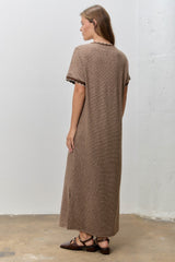 woman wearing a brown striped maxi dress with short sleeves and scalloped edges, viewed from the back