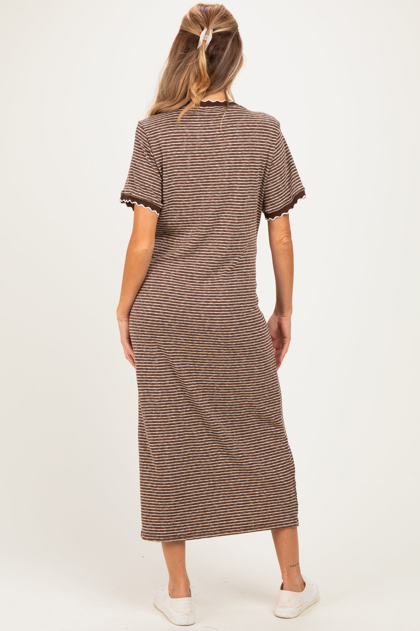 woman wearing a striped brown maternity maxi dress with short sleeves, showing her back and light shoes