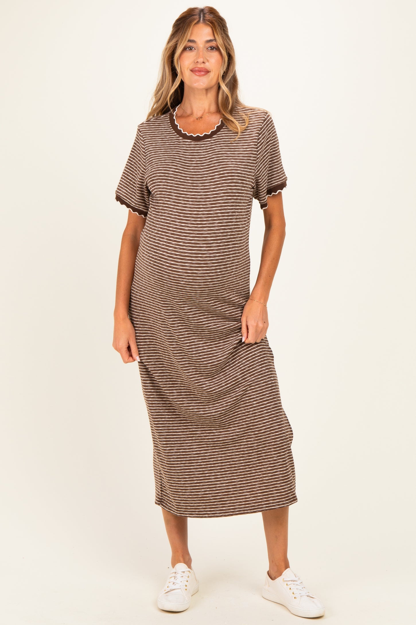 woman wearing a striped brown maternity dress with short sleeves and scalloped neckline, showing her baby bump