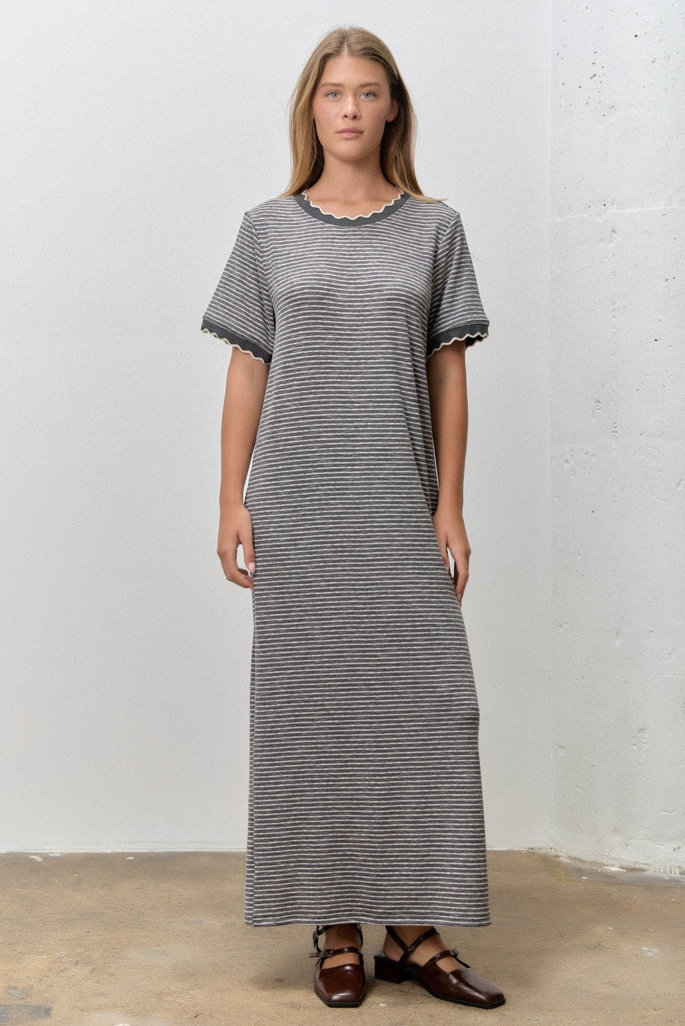 woman wearing a long striped grey maxi dress with scalloped edges and short sleeves