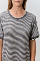 woman wearing a gray striped t-shirt with scalloped neckline and sleeve edges