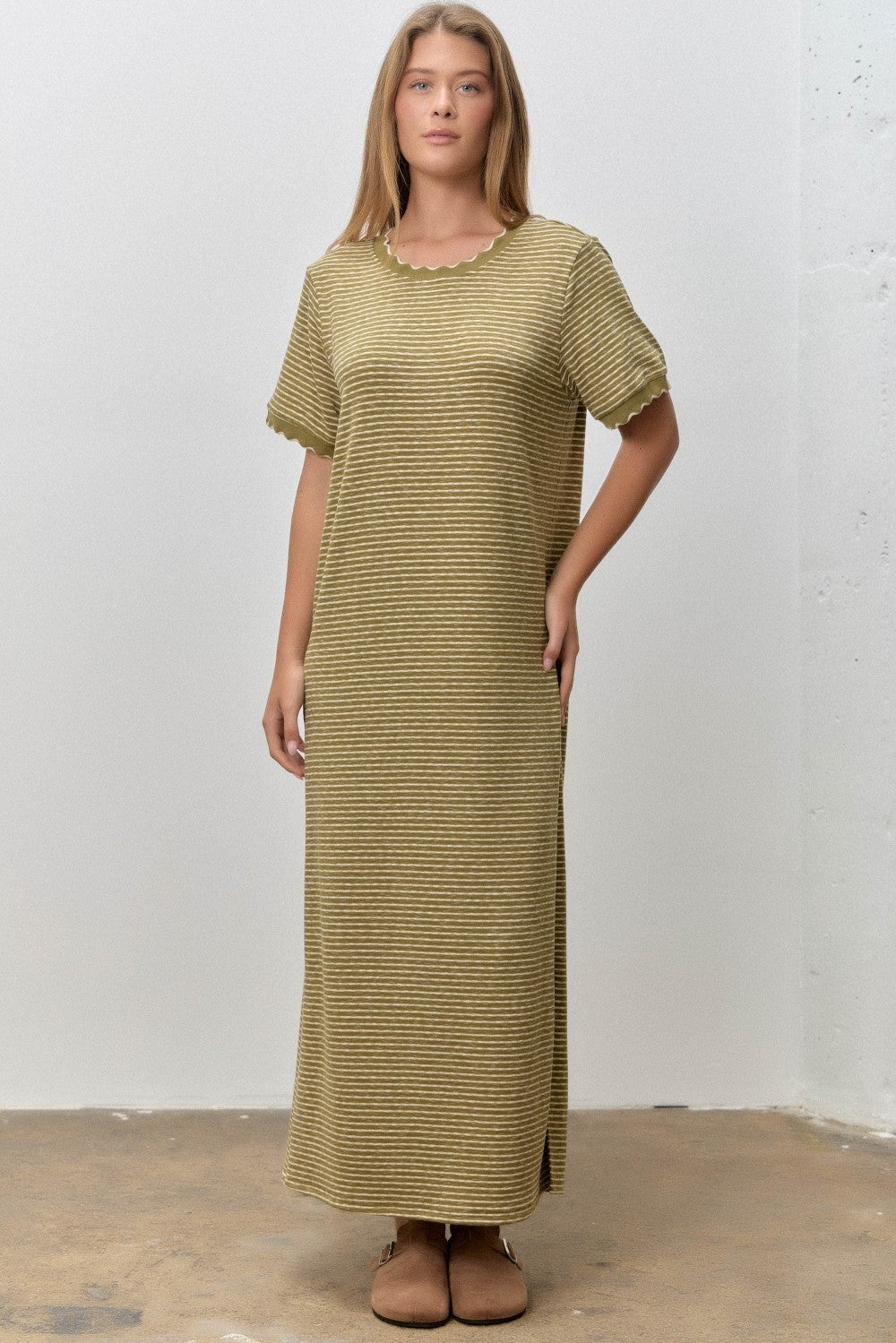 woman wearing a light olive green striped maxi dress with short sleeves and a scalloped neckline