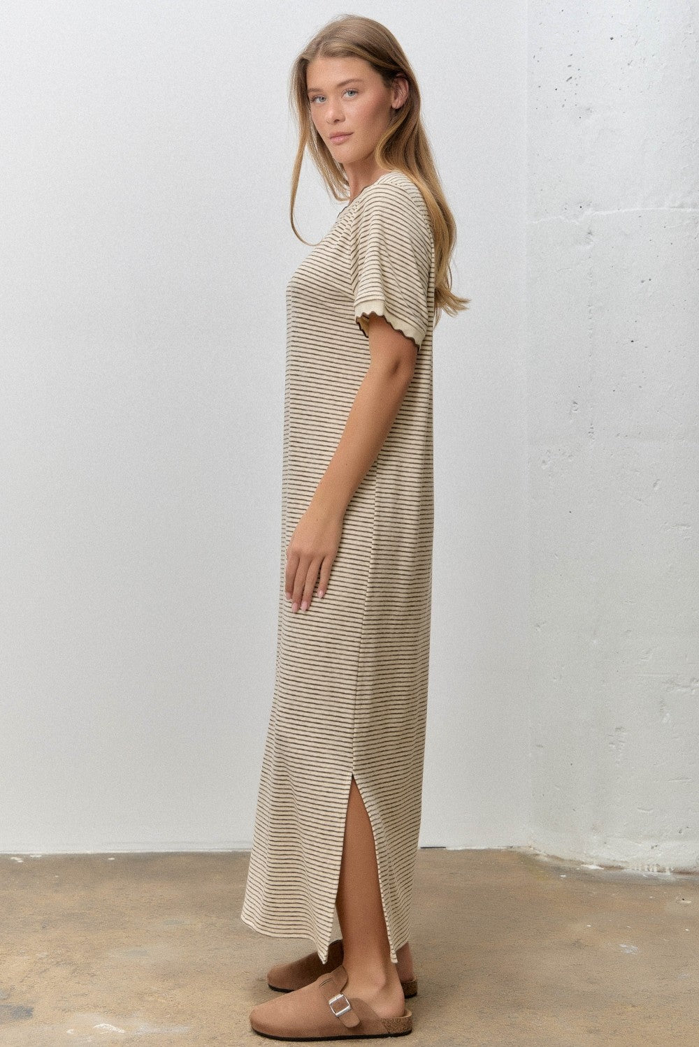 woman wearing a beige striped short sleeve maxi dress with side slits and brown sandals