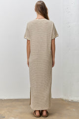 woman wearing a beige striped maxi dress with short sleeves and side slits, viewed from the back