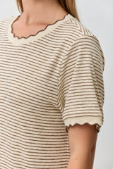 woman wearing a cream and brown striped t-shirt with scalloped edges on the sleeves and neckline