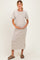 woman wearing a striped beige and brown maternity dress, gently cradling her baby bump