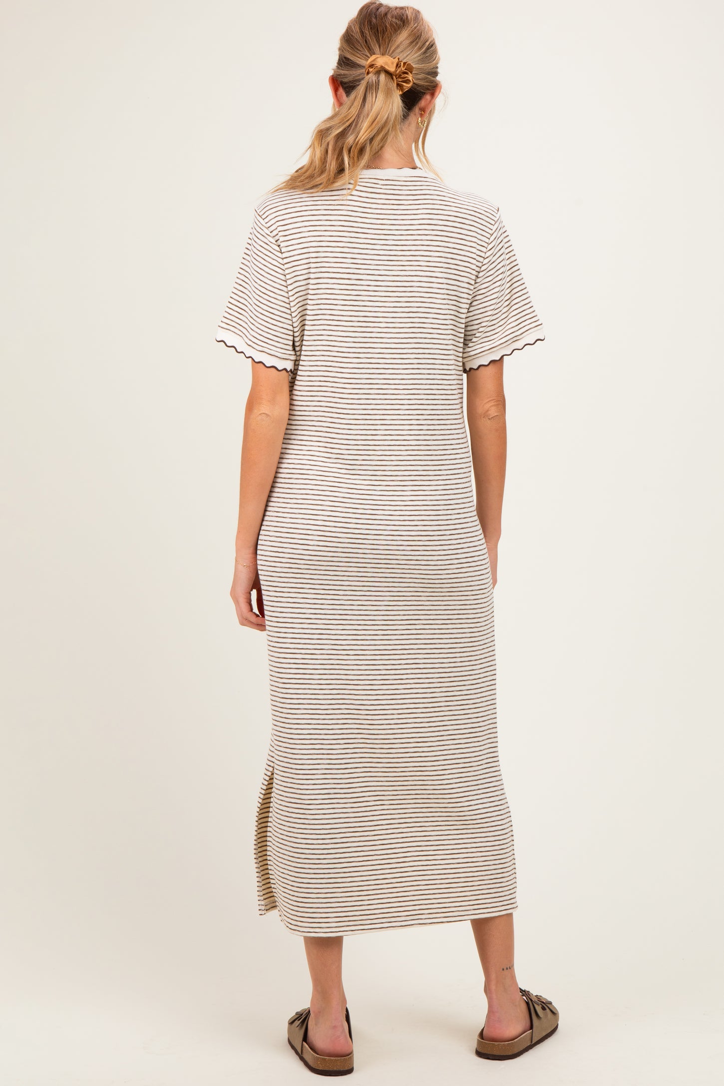 woman wearing a beige and brown striped maternity dress with short sleeves and a side slit