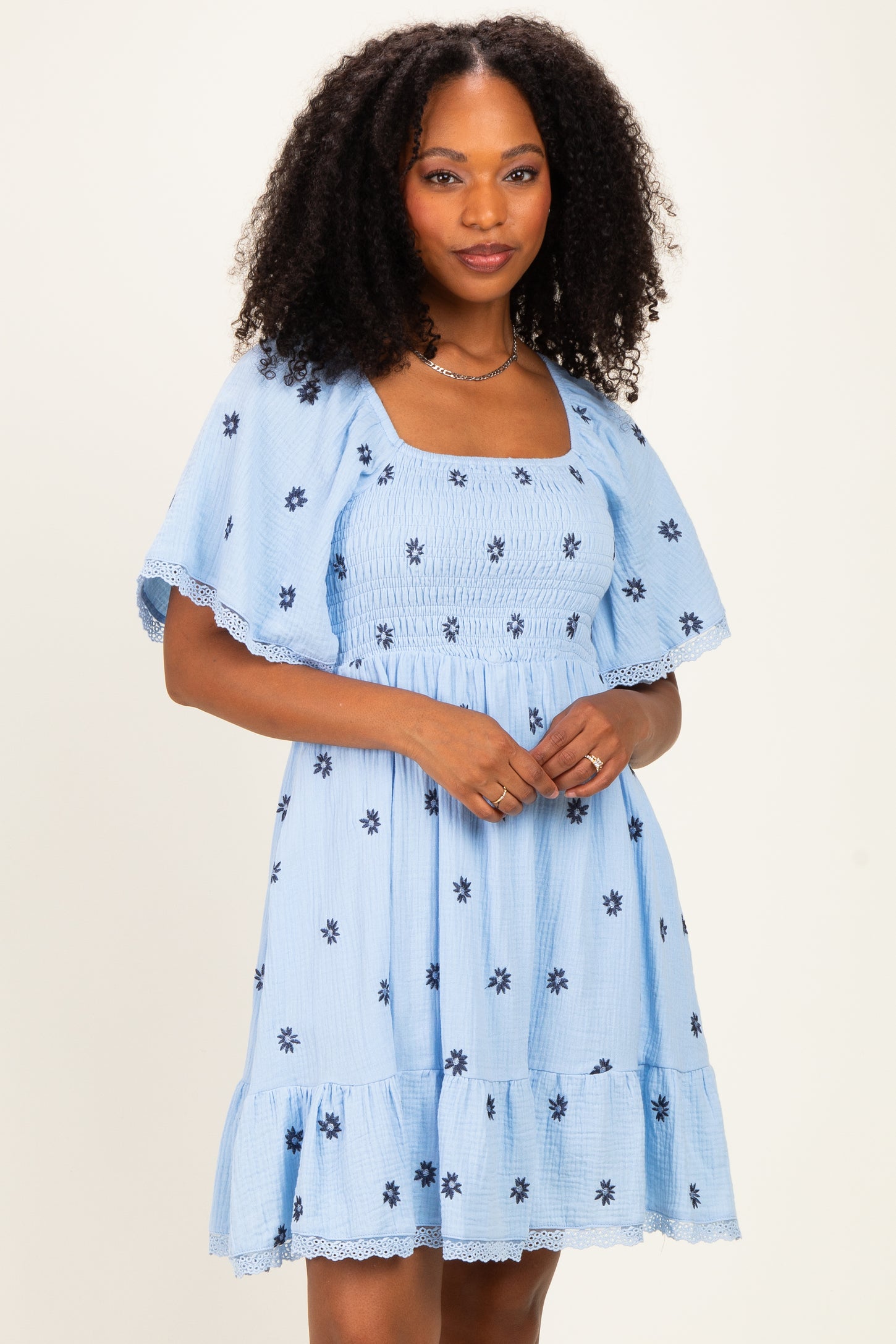 woman wearing a light blue floral print dress with puff sleeves and a tiered skirt
