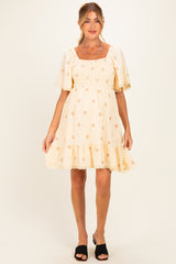 woman wearing a cream floral maternity dress with puff sleeves and ruffled hem