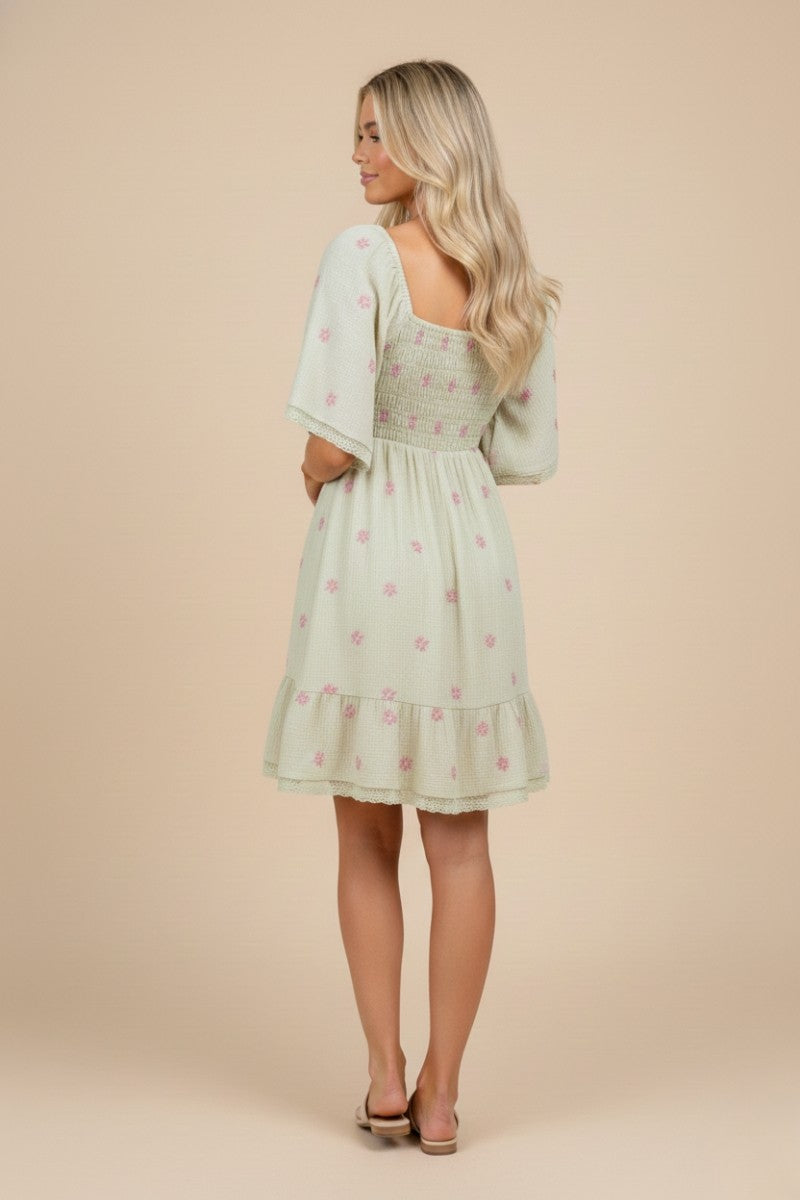 woman wearing a mint green floral smocked back dress with ruffled hem and short sleeves