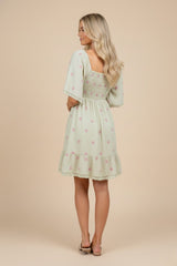 woman wearing a mint green floral smocked back dress with ruffled hem and short sleeves