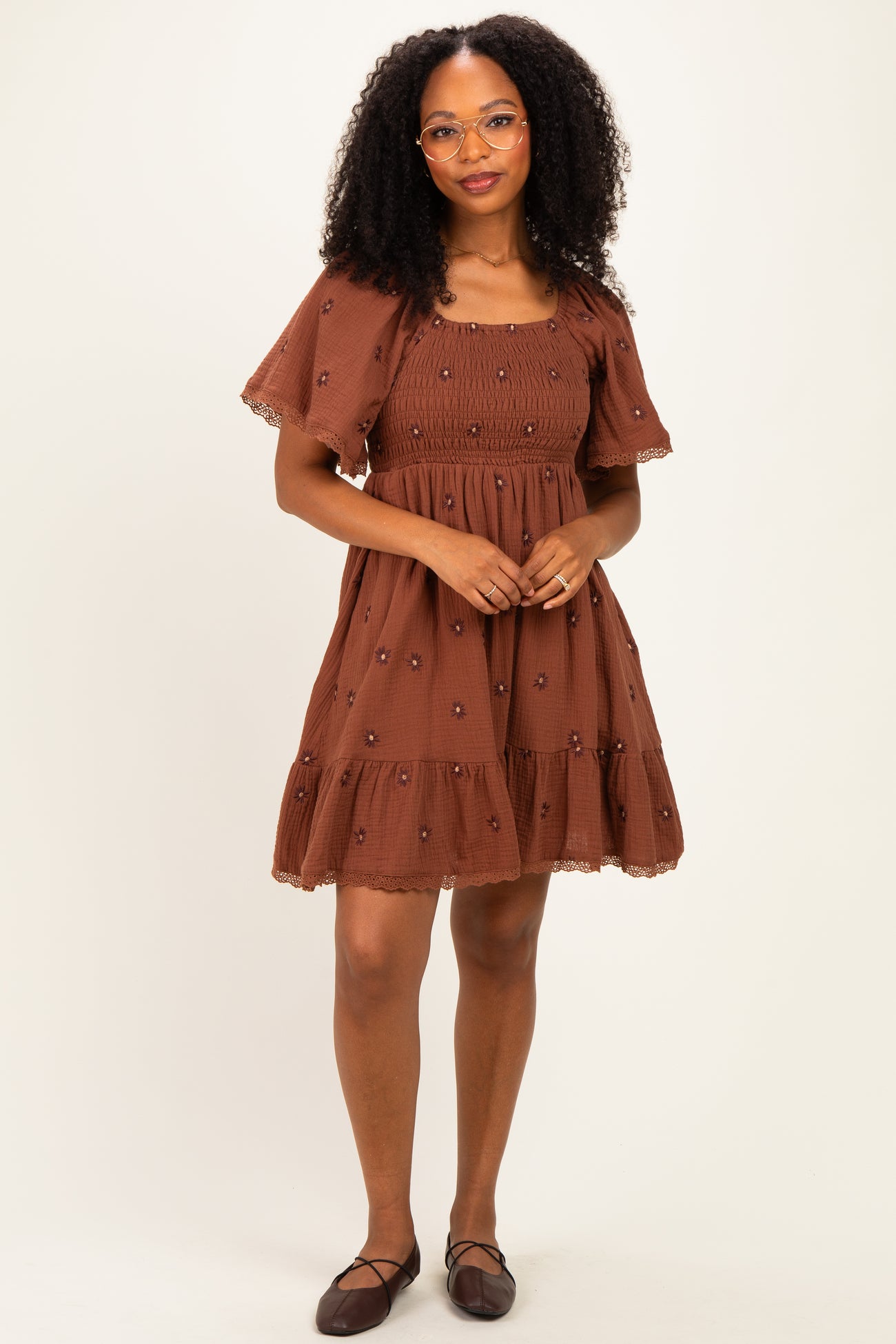 woman wearing a brown embroidered short dress with puff sleeves and a tiered skirt