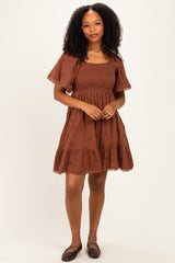 woman wearing a brown embroidered short dress with puff sleeves and a tiered skirt