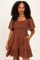 woman wearing a brown short sleeve smocked dress with floral embroidery and pockets