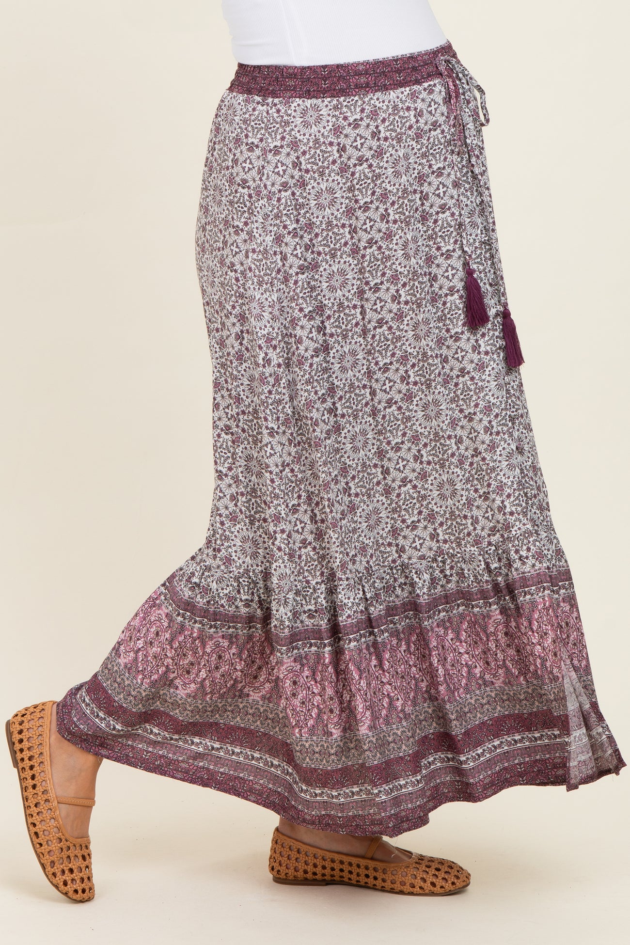woman wearing a purple floral maternity maxi skirt with tassel detailing and a stretchy waistband