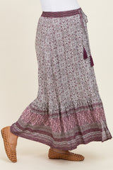 woman wearing a purple floral maternity maxi skirt with tassel detailing and a stretchy waistband