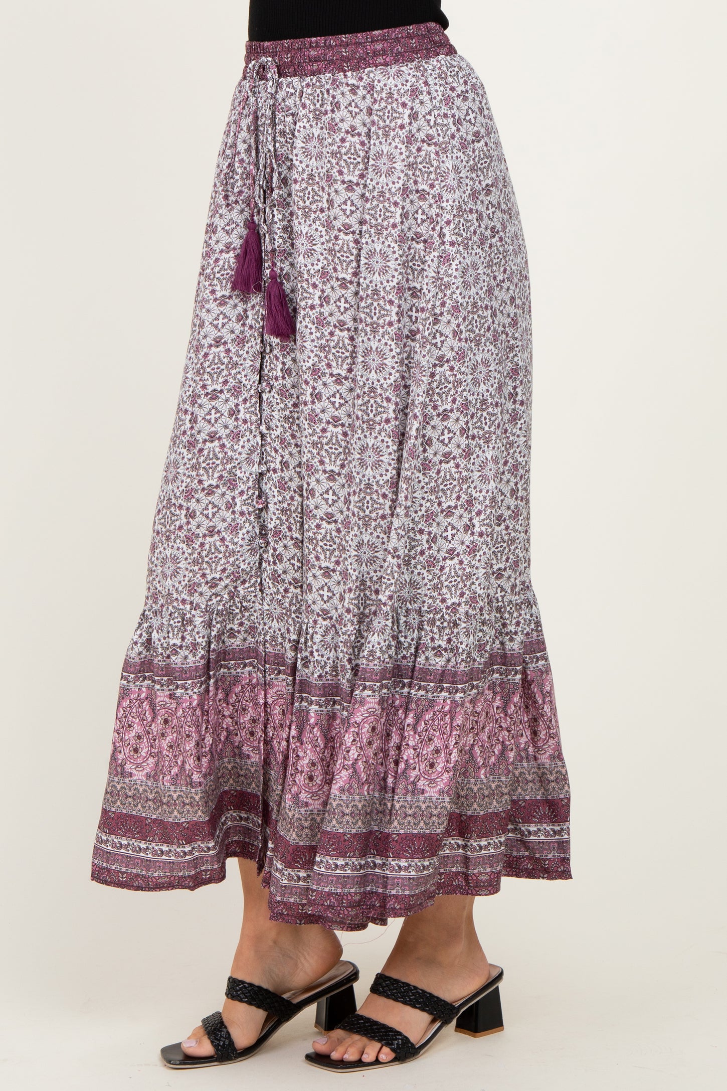 woman wearing a purple and white floral print maxi skirt with a tiered hem and tassel details