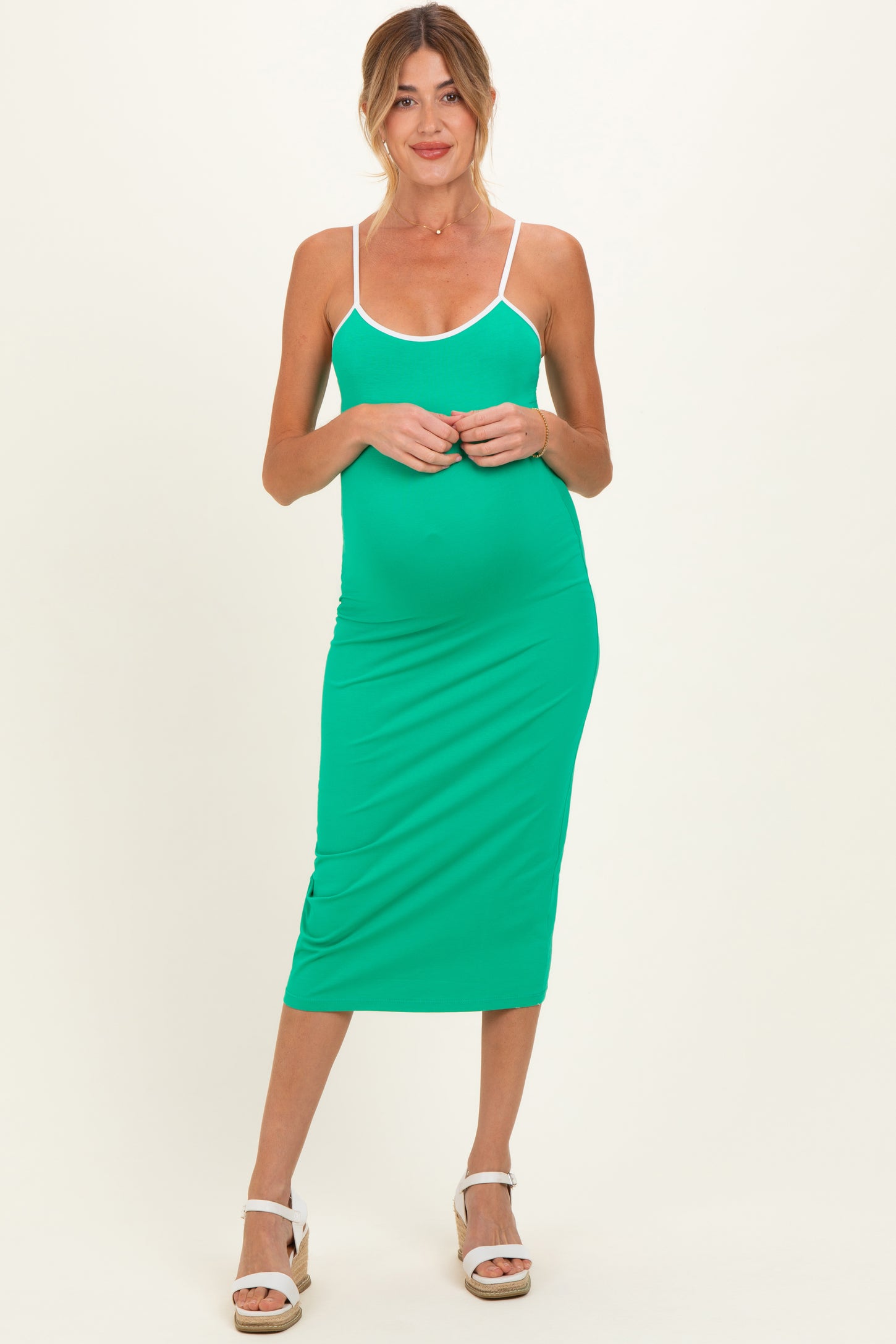 woman wearing a green maternity dress with spaghetti straps and a form-fitting style, showing her baby bump