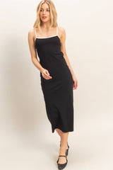 woman wearing a black spaghetti strap midi dress with white trim and strappy heels