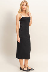 woman wearing a black spaghetti strap midi dress with white trim and black flats